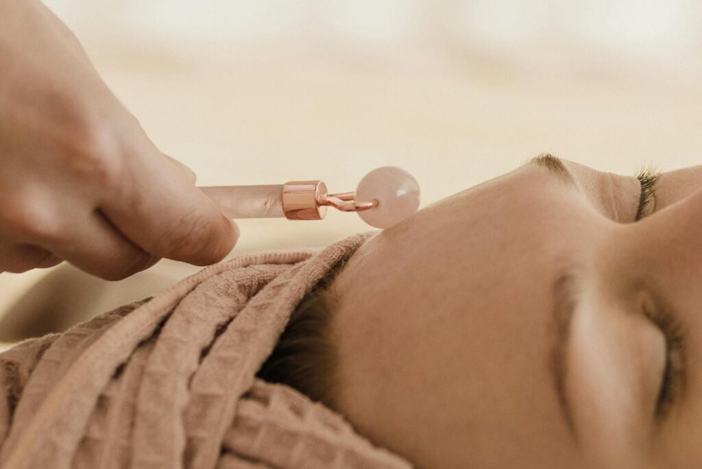 A Person Using a Facial Roller on a Womans Face